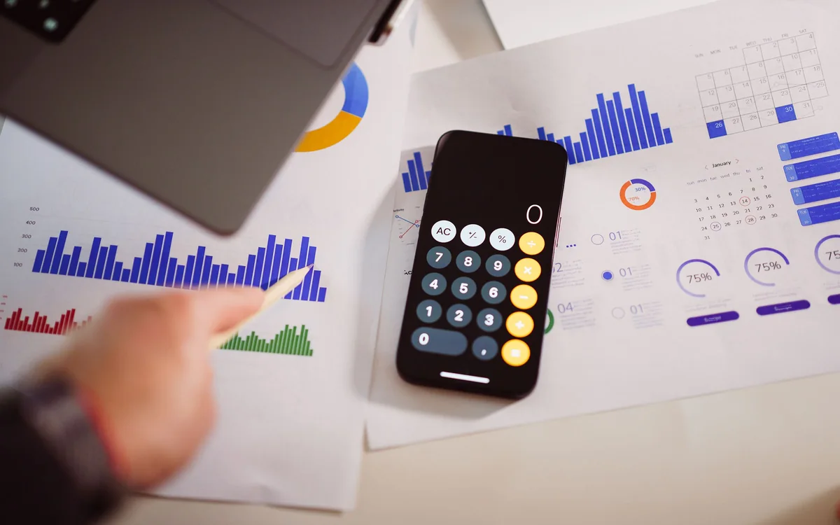 Business and finance documents, calculator, and laptop arranged on an office table, representing business loans and financing.